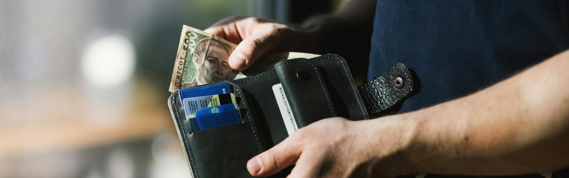 Close-up of a man holding a wallet with cash and credit cards, indoors.